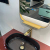 Black oval sink with gold faucet on a red countertop, mirror above