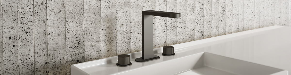 Carimali basin faucet installed against a textured stone wall, from Aquadesign’s official collection imagery